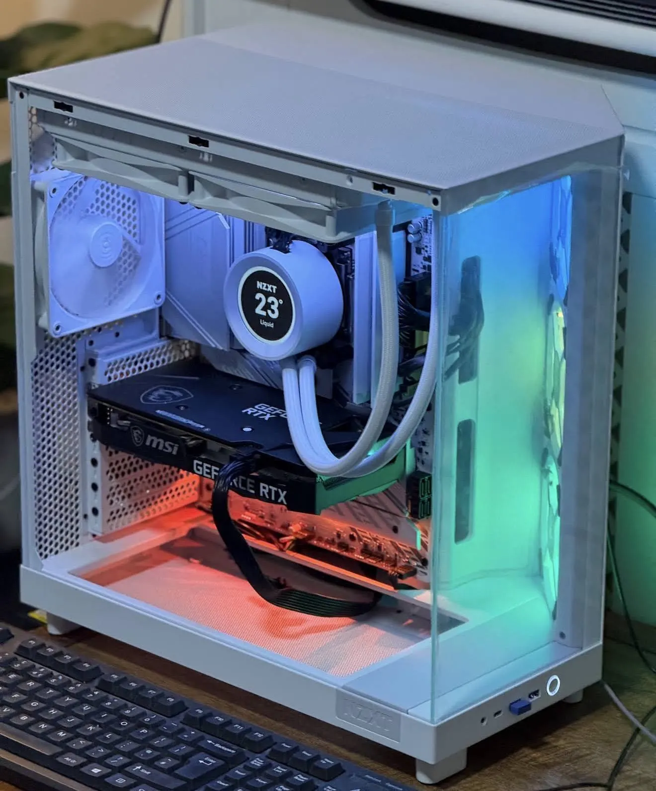 White PC case with a tempered-glass side, a liquid cooler and lit fans.
